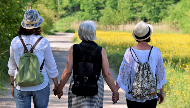 Three women walk hand-in-hand down a path together