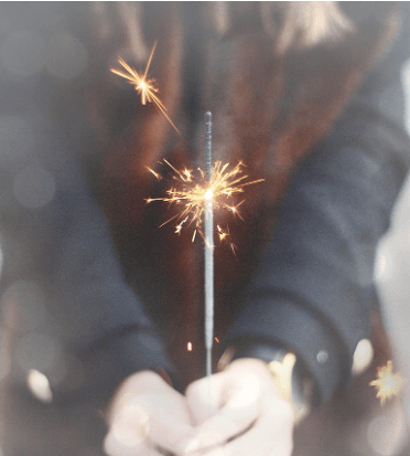 Close up of a woman holding a sparkler.