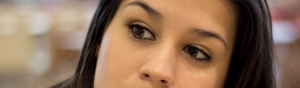 Close up image of a dark-haired woman's eyes' and nose as she looks to the side thoughtfully