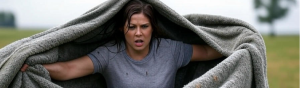 AI image of a woman who's had enough with the heavy blaket of shame and is throwing it off as it has covered her head and shoulders. Her face is intense